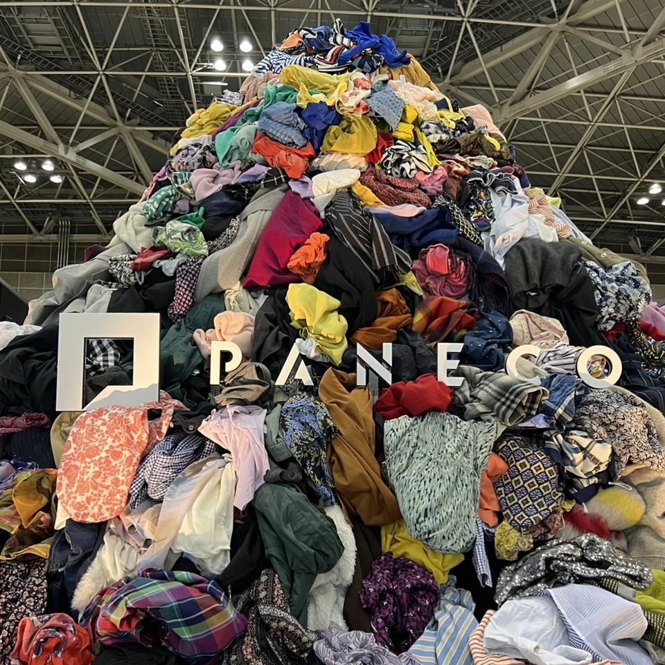 色とりどりの衣類が積み重なり、PANECO®のロゴを配した展示